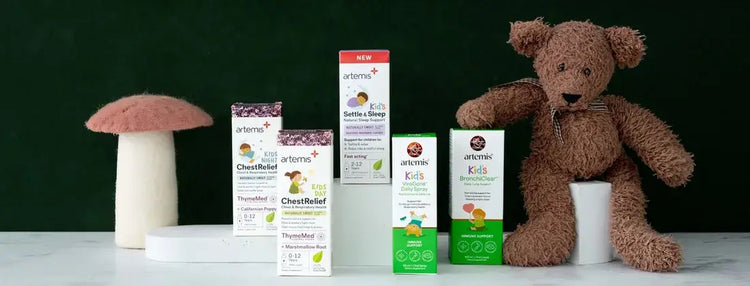 artemis kid's products arranged on a white pedestal next to a brown teddy bear and a mushroom prop.