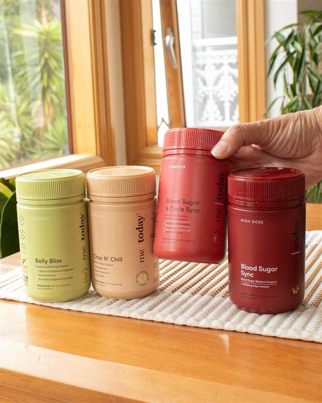 Four supplement containers on a wooden surface with a window in the background.