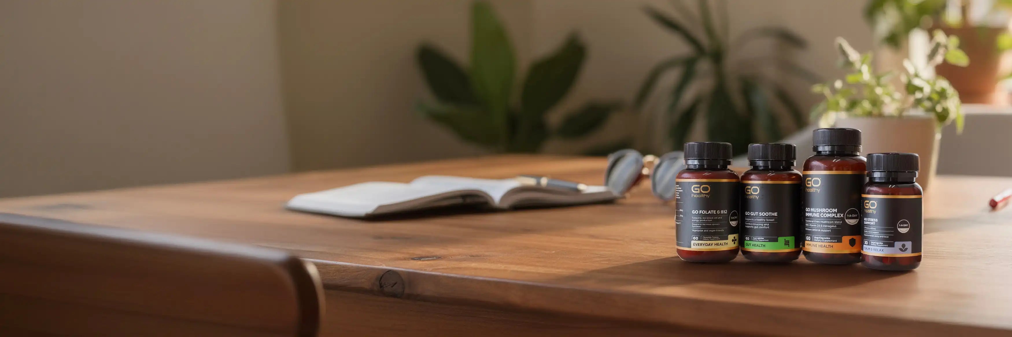 Four small supplement bottles on a wooden table with a blurred background.
