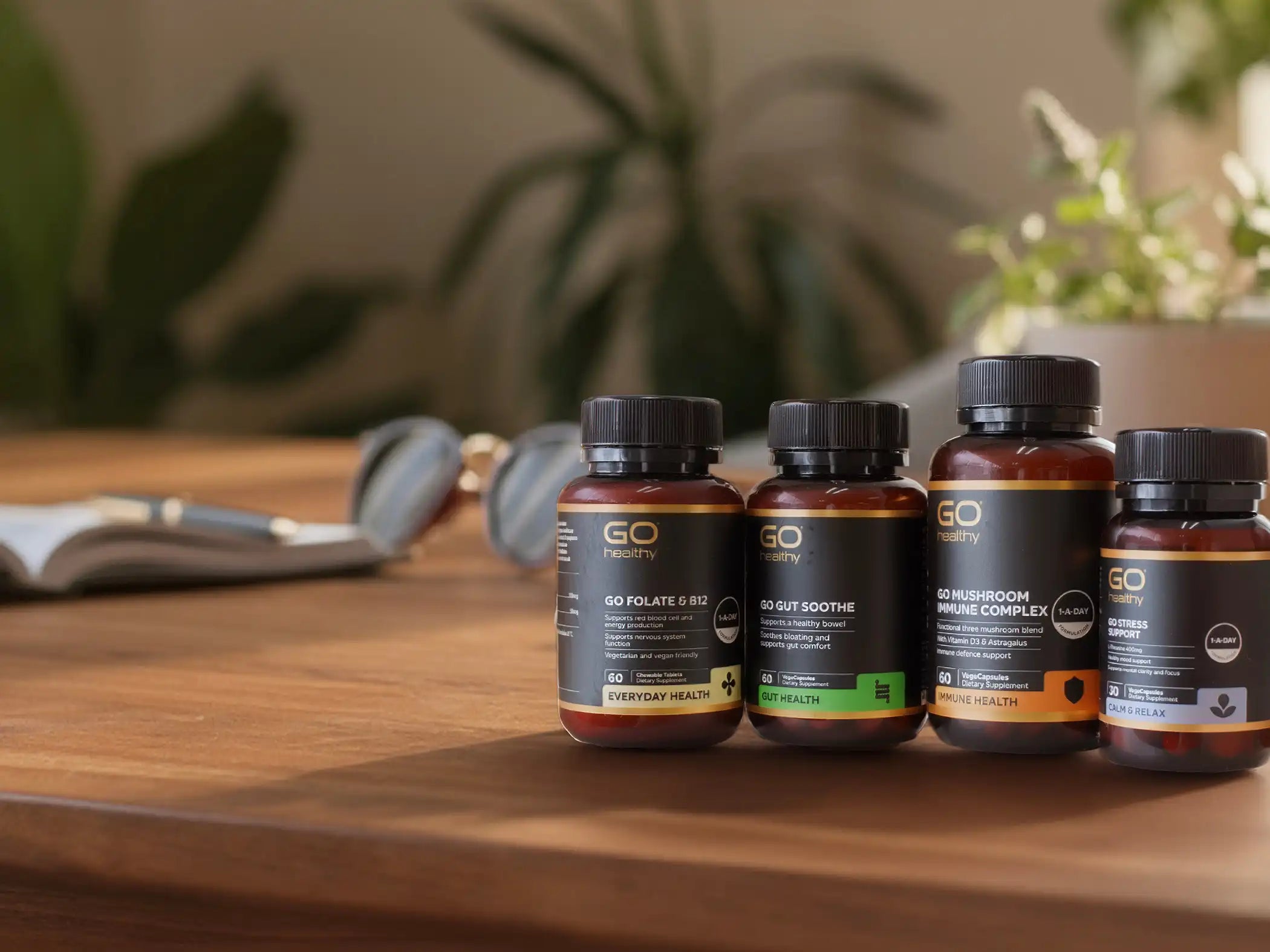 Four small supplement bottles on a wooden table with a blurred background.