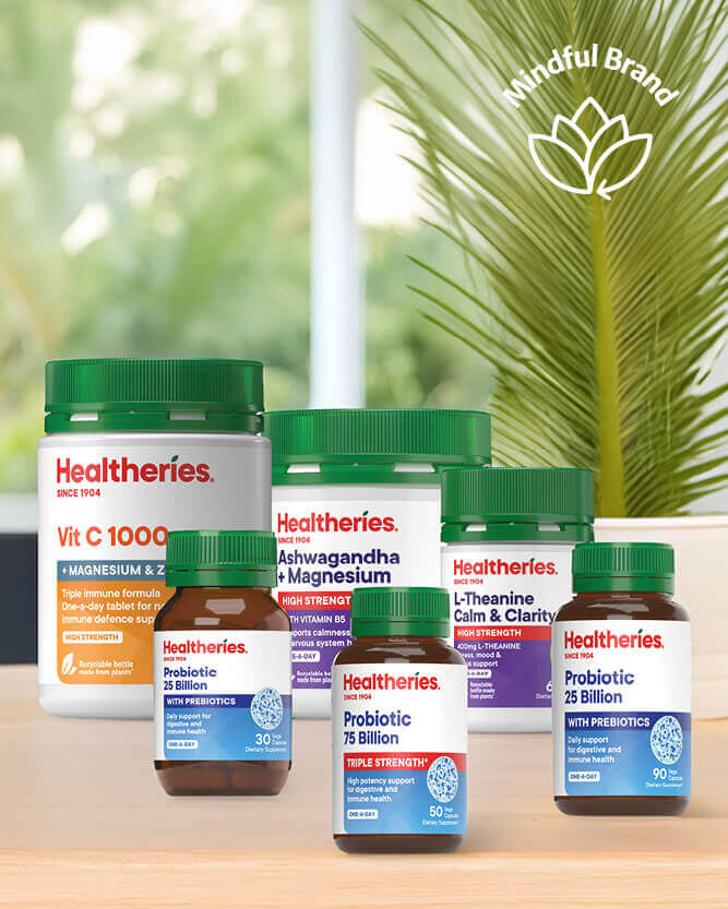 Collection of Healtheries supplement bottles on a wooden surface with a blurred natural background.