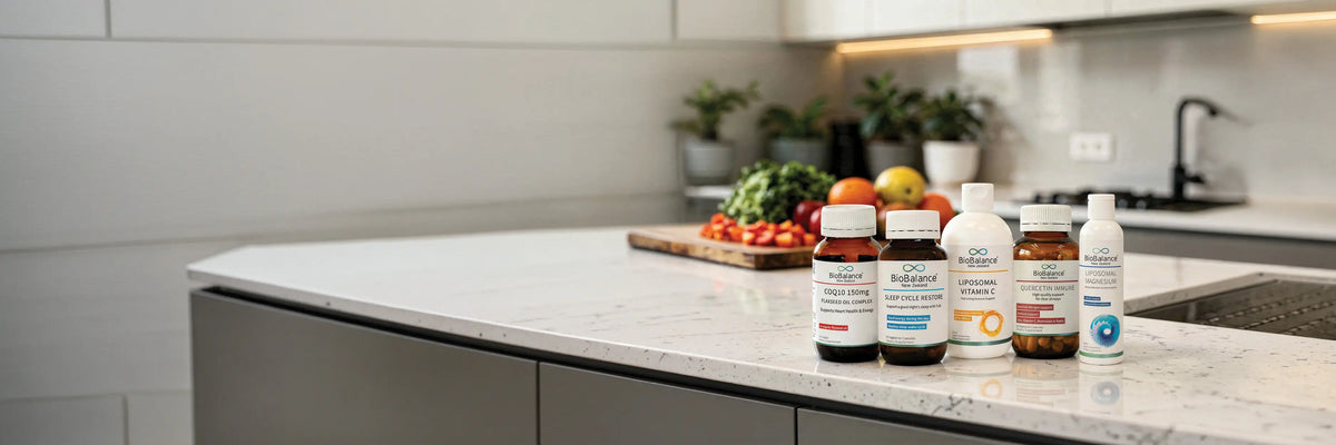 5 BioBalance products on a kitchen bench with a wooden board of chopped vegetables and fruit stacked up.