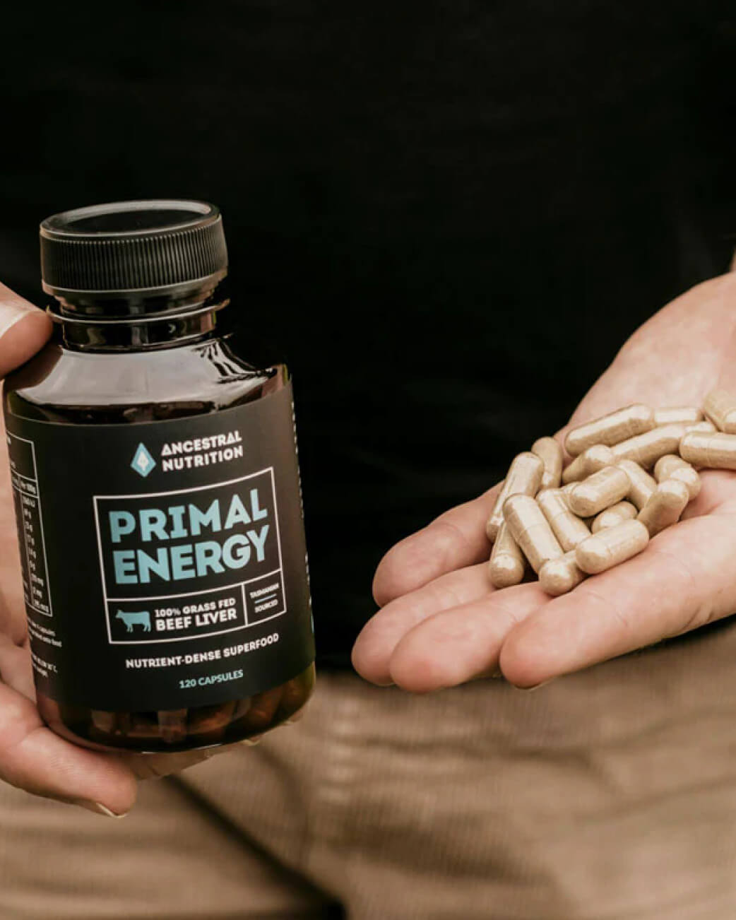 Bottle of 'Primal Energy' supplement held by a person with capsules in the other hand