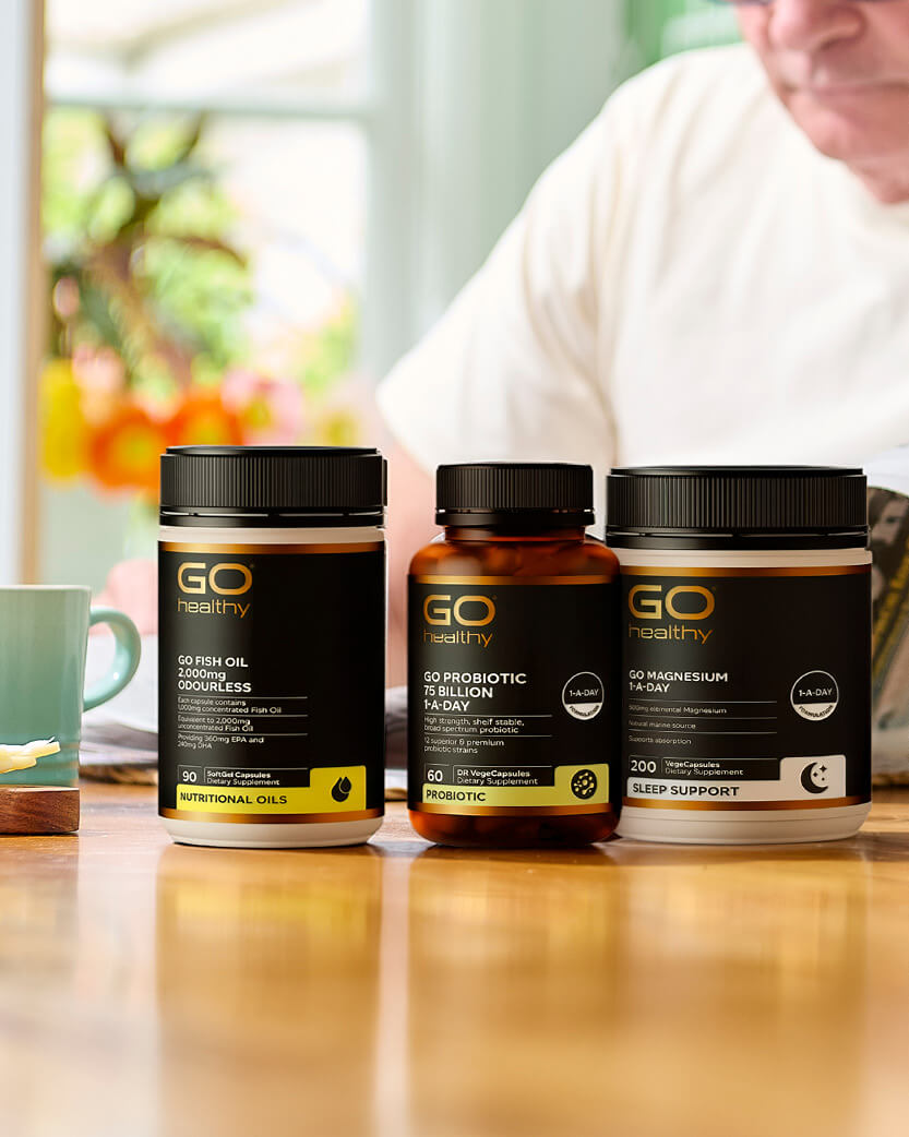 Three GO Healthy supplement bottles on a table with a blurred background.