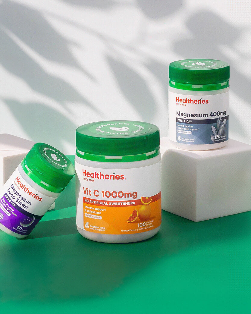 Three Healtheries supplement jars on a green surface with a white background.