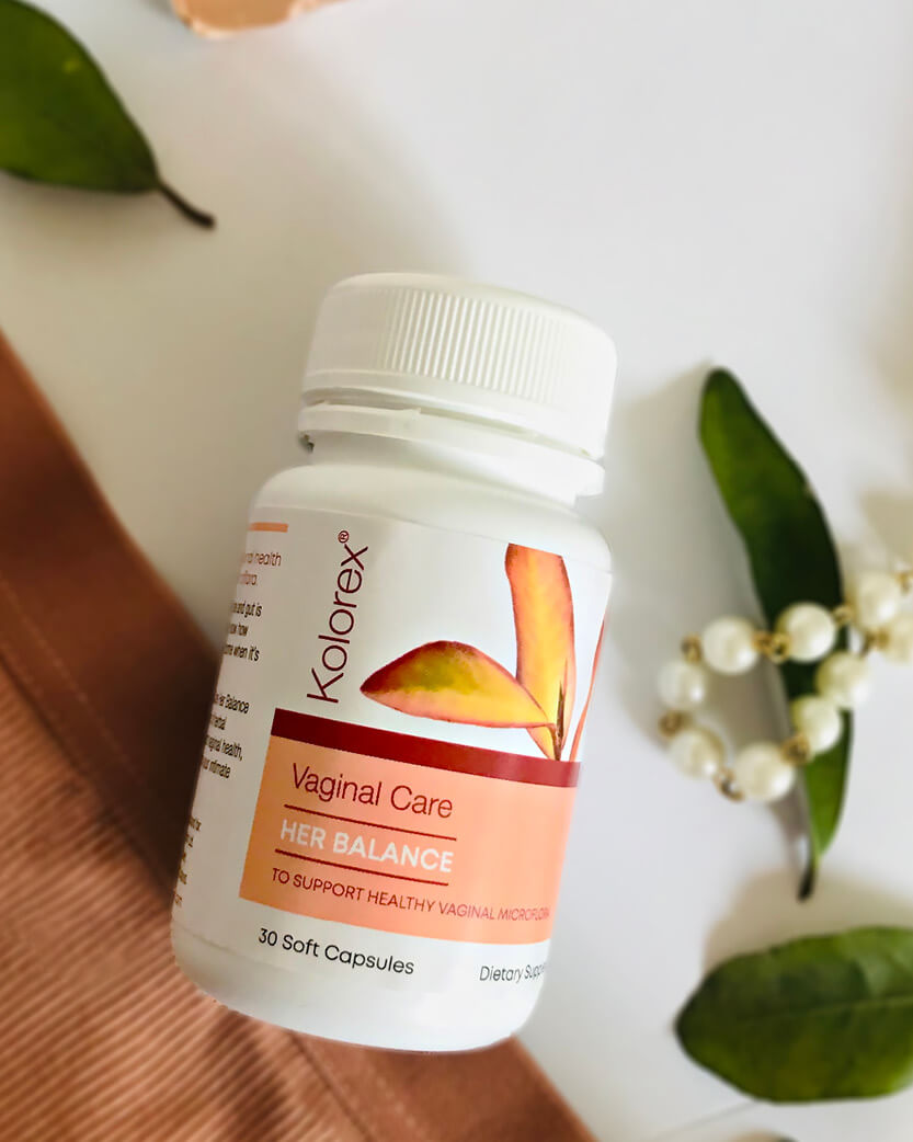 Kolorex Vaginal Care supplement bottle on a wooden surface with leaves in the background.
