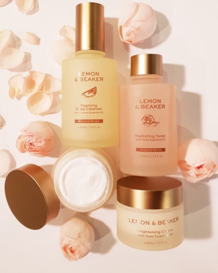 Lemon & Beaker skincare products with flowers on a light background.