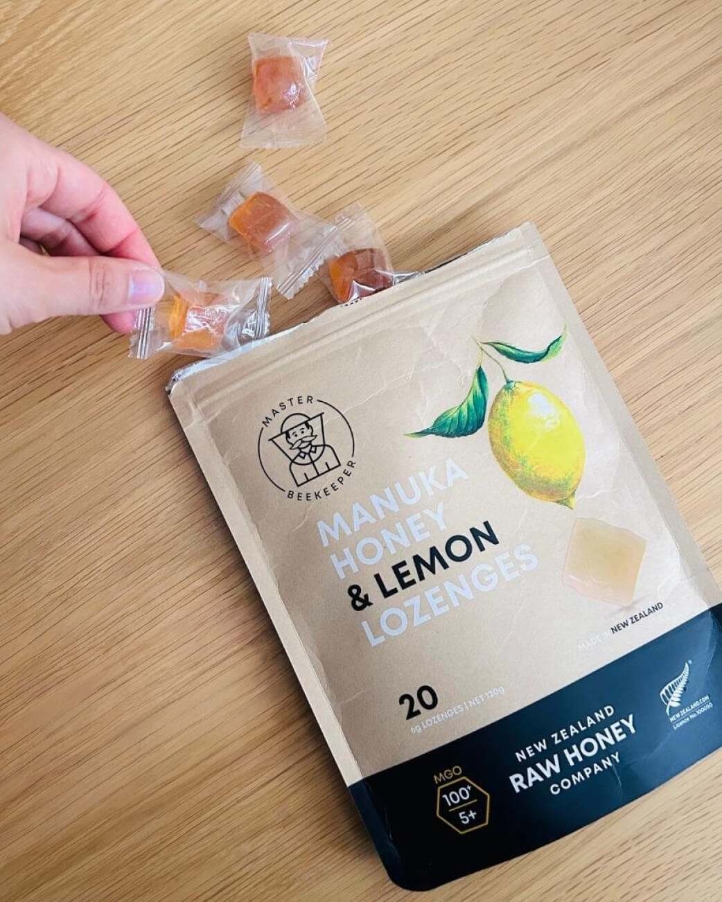 Manuka Honey & Lemon Lozenges package with lozenges on a wooden surface.