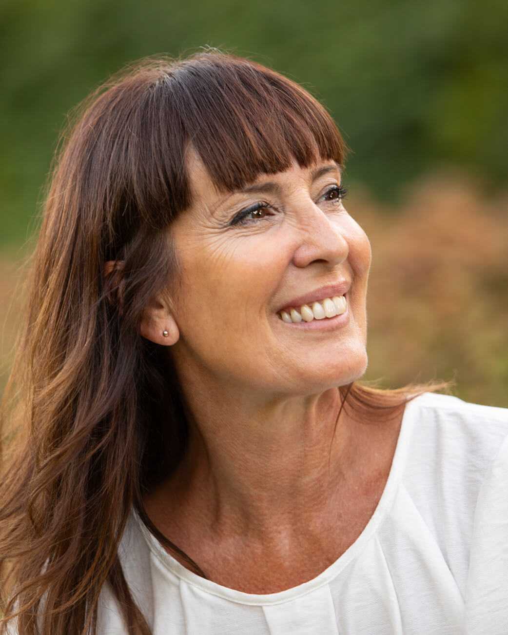 Woman with long brown hair smiling outdoors.