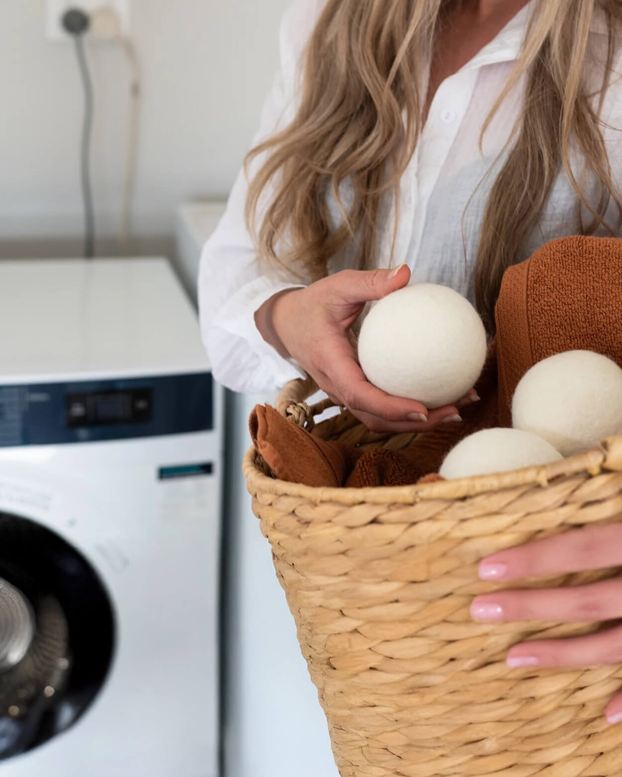 Person holding a basket with laundry balls in a laundry room.