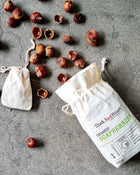 Organic soapberries with two white drawstring bags on a grey surface.