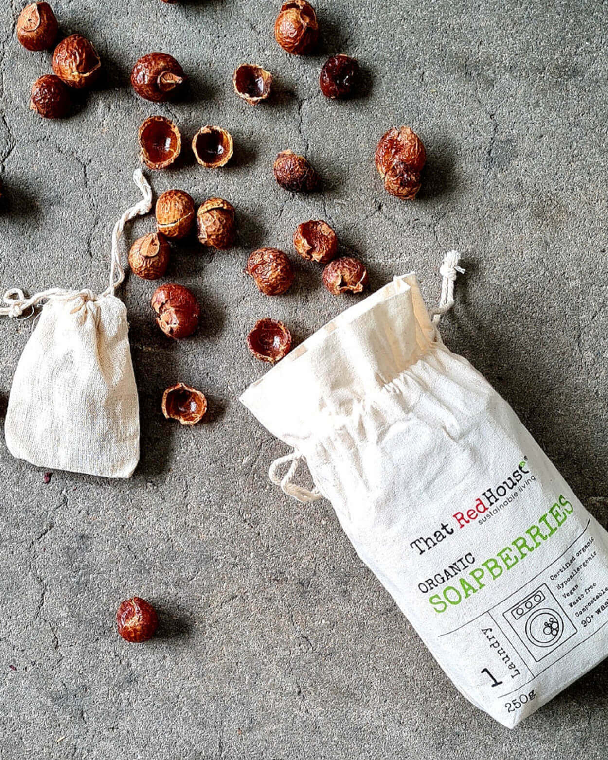 Organic soapberries with two white drawstring bags on a grey surface.