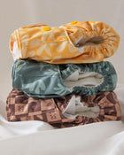 Stack of three patterned cloth diapers on a white background.