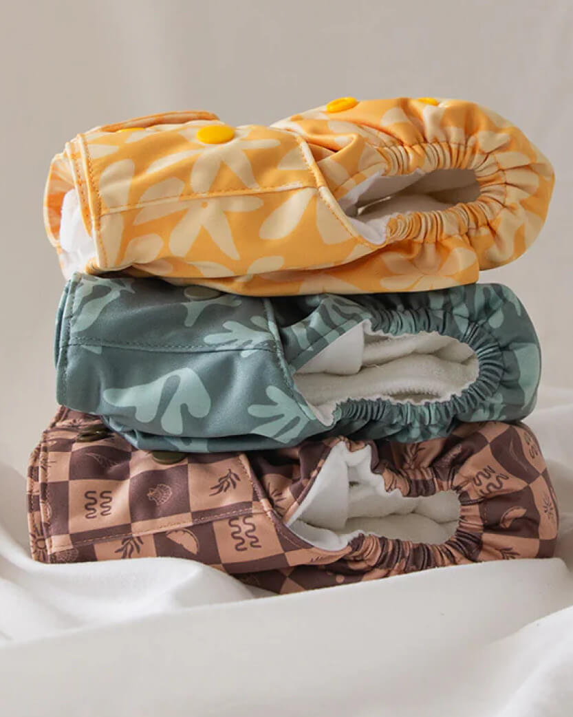 Stack of three patterned cloth diapers on a white background.