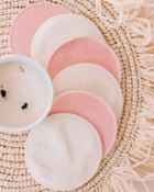 Set of pink and beige circular fabric pads on a textured woven surface.