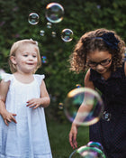 Two young girls playing with bubbles outdoors.