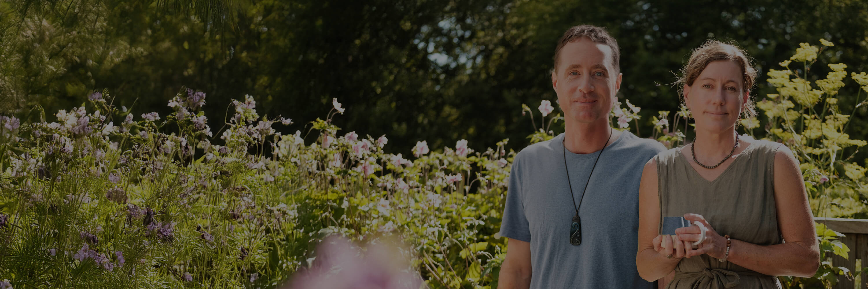 Woman and man standing together outside, surrounded by plants.