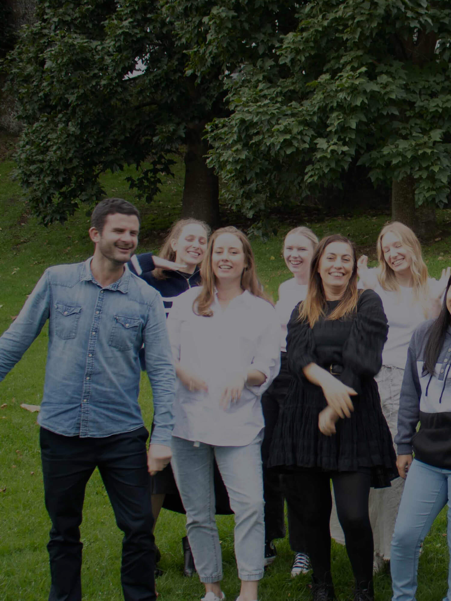 Group of people standing outdoors in a park-like setting.