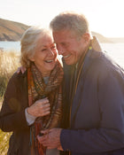 Senior couple embracing outdoors with a scenic background.