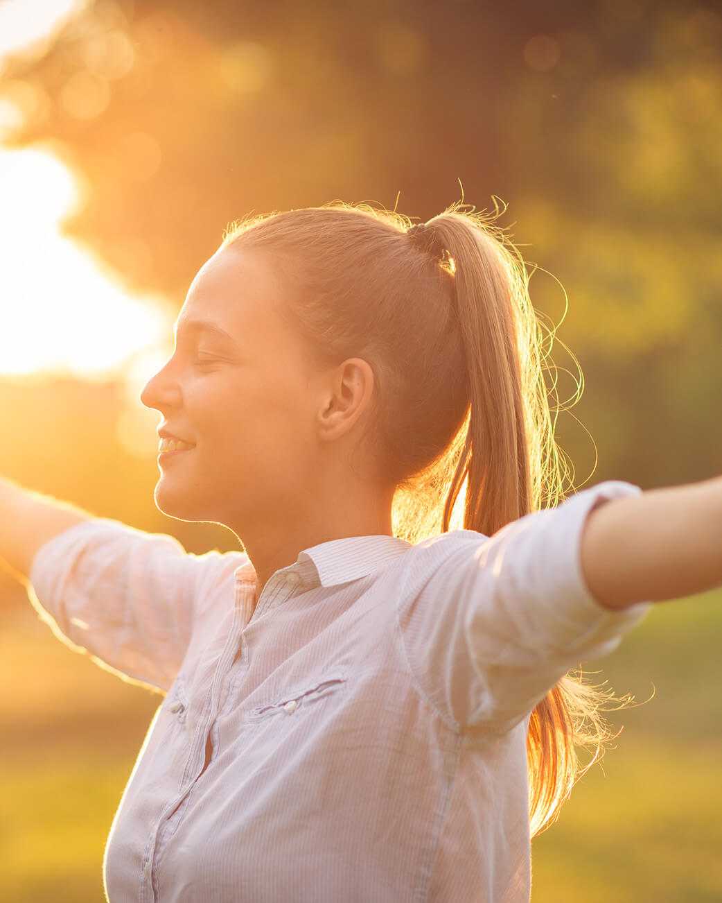 Woman in a sunny setting stretching out her arms.