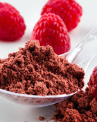 Cocoa powder in a spoon with raspberries on a white background