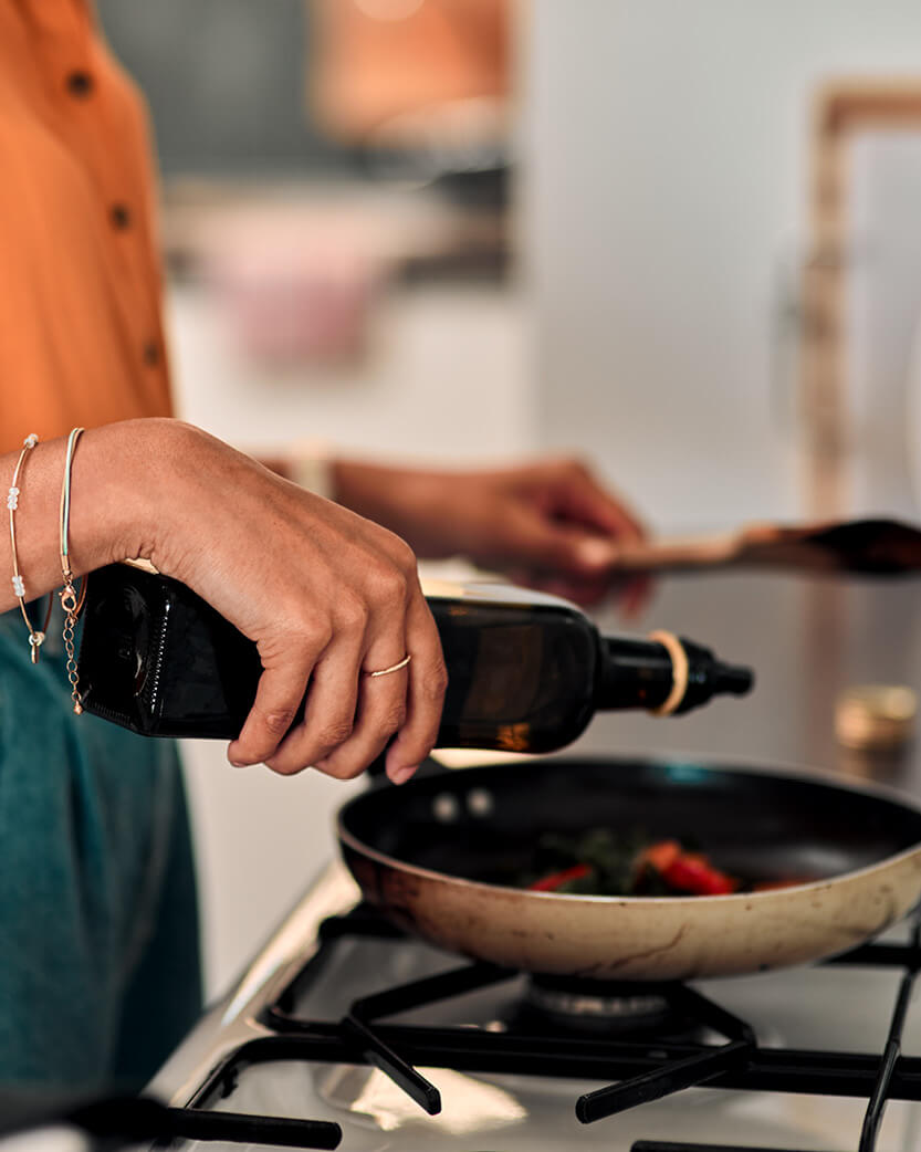 Person pouring oil into a frying pan on a stove