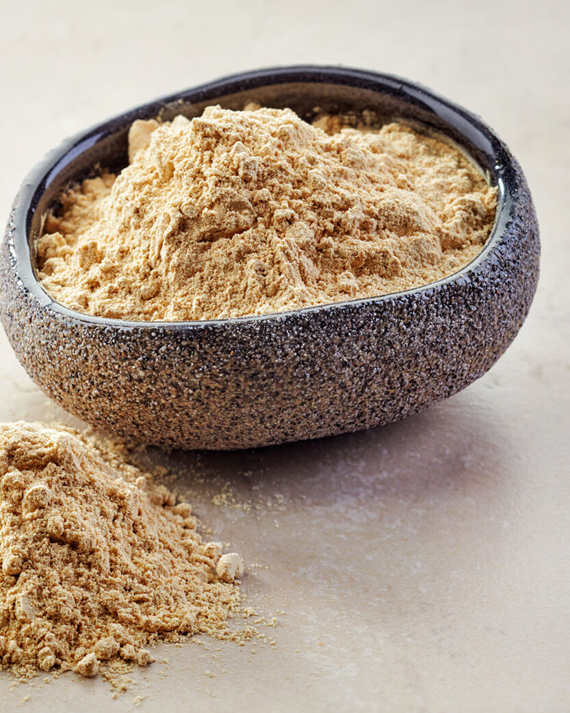 Bowl of brown powder on a light surface.