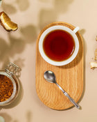 Tea cup on a wooden tray with a spoon and jar of spices on a beige background