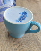 White cup of coffee with brown sugar on a matching saucer with mushrooms