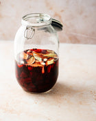 Glass jar with spices and liquid on a light surface