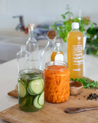 Sliced carrots and cucumbers in a jar on a chopping board.