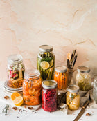 Collection of glass jars with pickled vegetables on a textured wall background