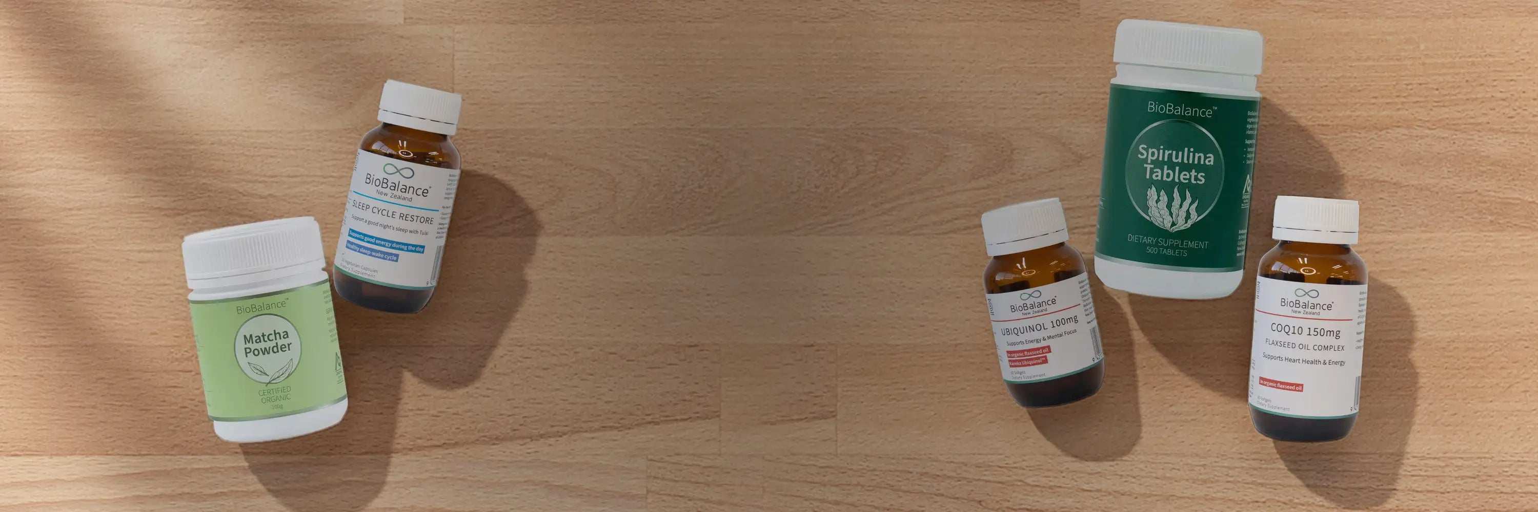 Four health supplement bottles on a wooden surface.