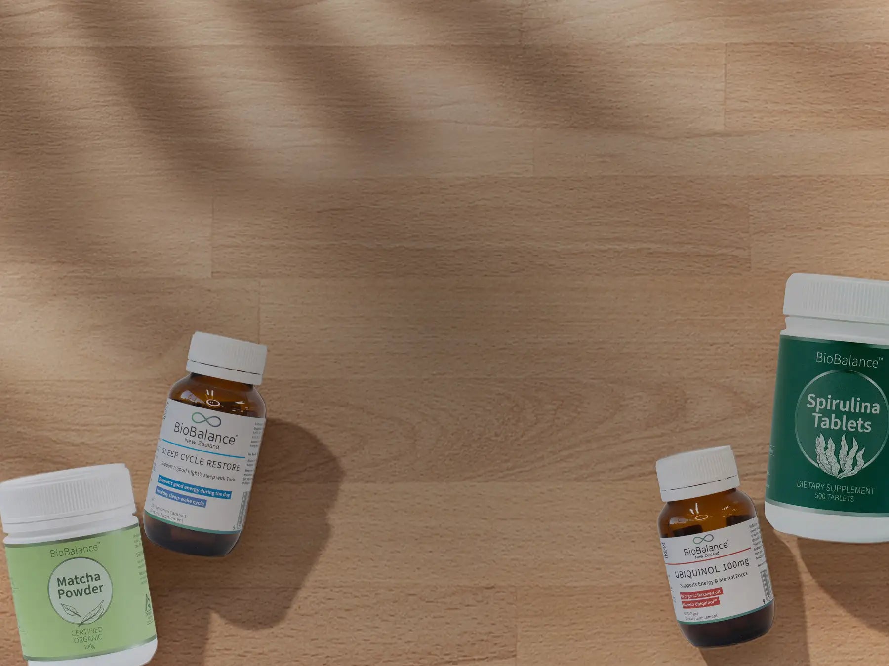 Four health supplement bottles on a wooden surface.