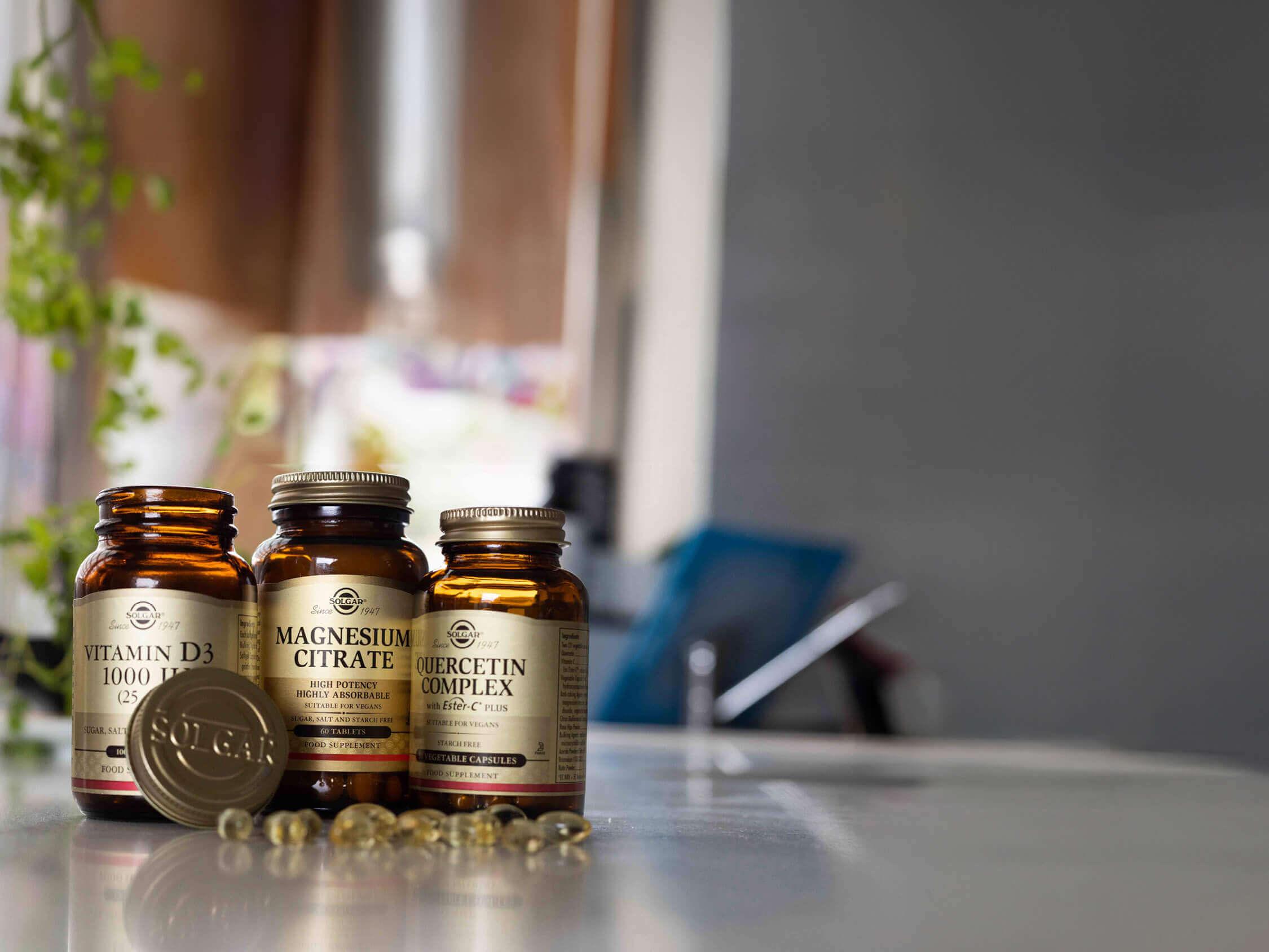 Three supplement bottles on a surface with a blurred indoor background.