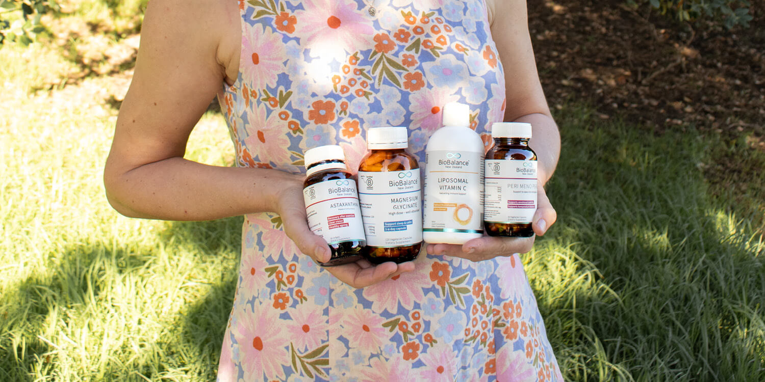 Person holding multiple supplement bottles outdoors.