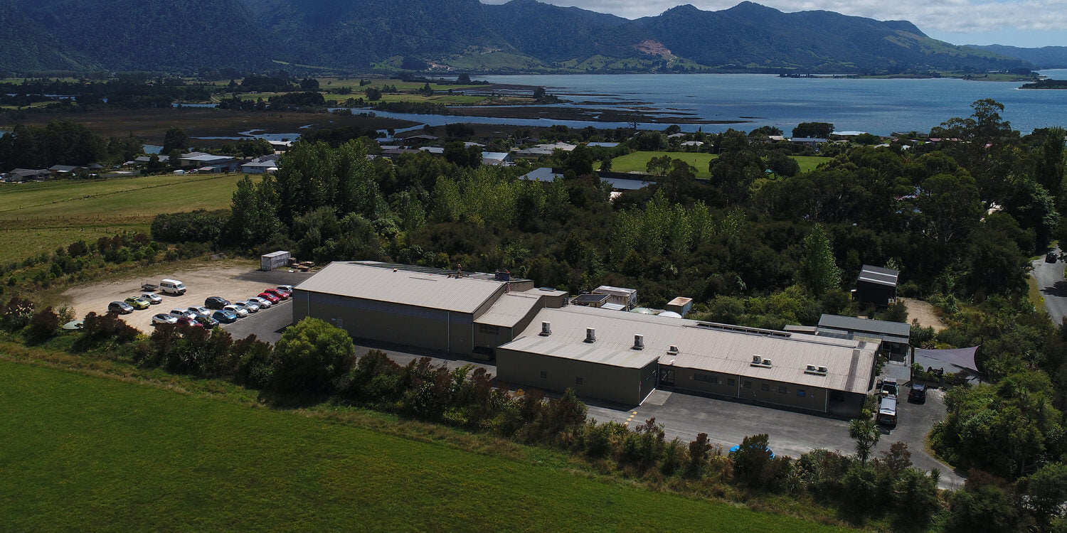Aerial view of a building complex with mountains and water in the background.