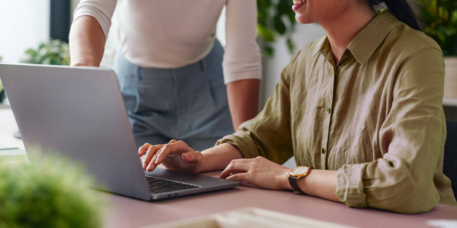 Two women working on laptops at a table.
