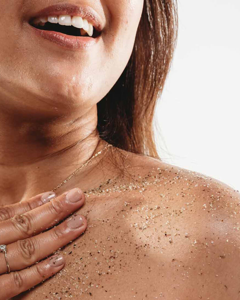 Close-up of a person's neck &shoulder with sand on the skin, wearing a necklace.