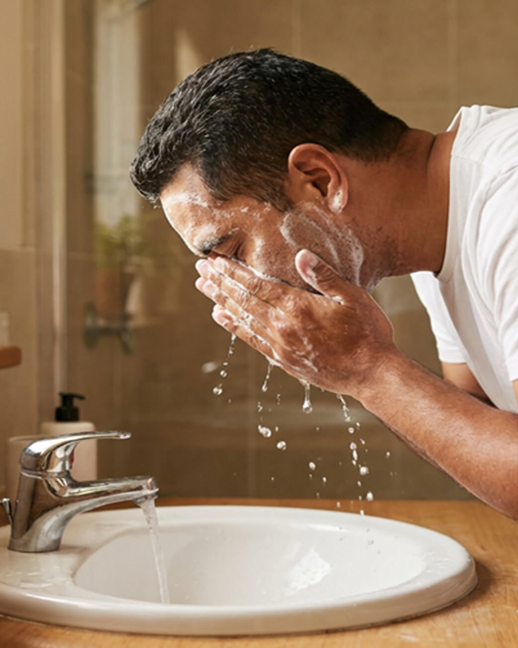 Man washing his face in a sink.