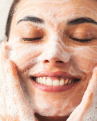 Woman with a foamy skincare product on her face.