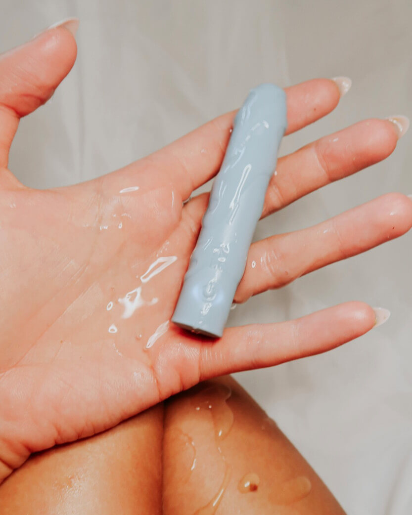 Hand holding a small blue cylindrical object with a white background.
