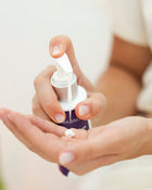 Hand holding a dropper with a small amount of liquid on a blurred background.