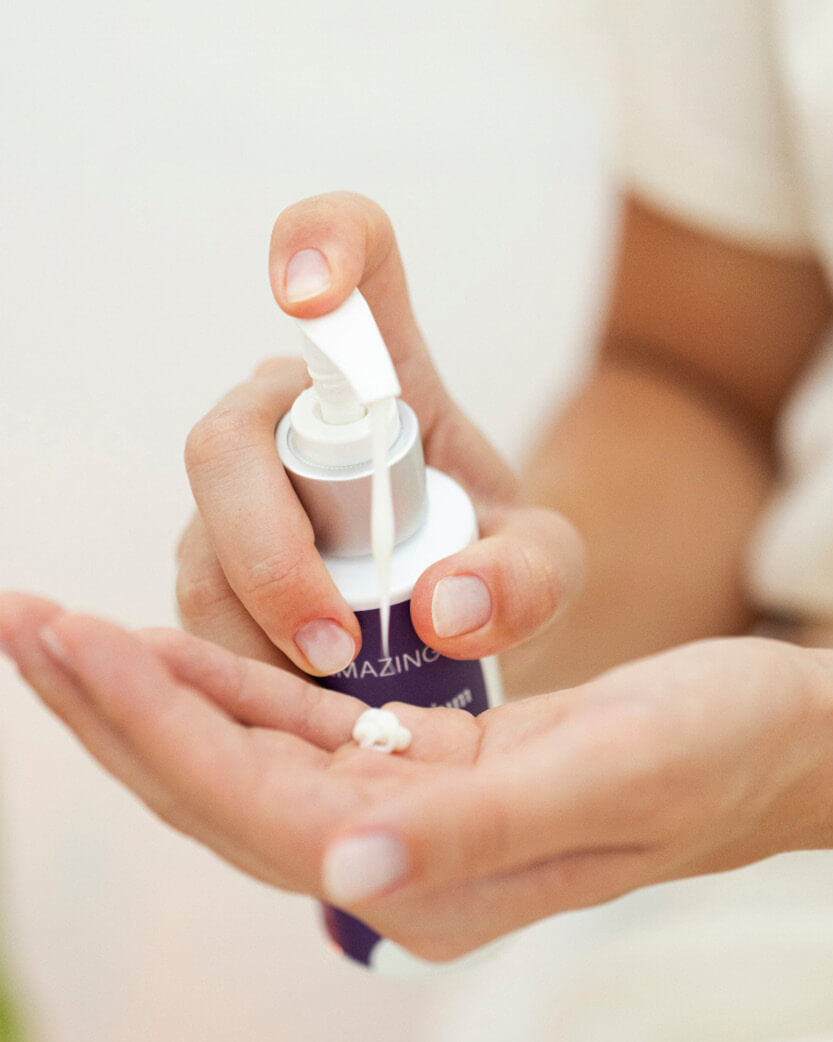 Hand holding a dropper with a small amount of liquid on a blurred background.