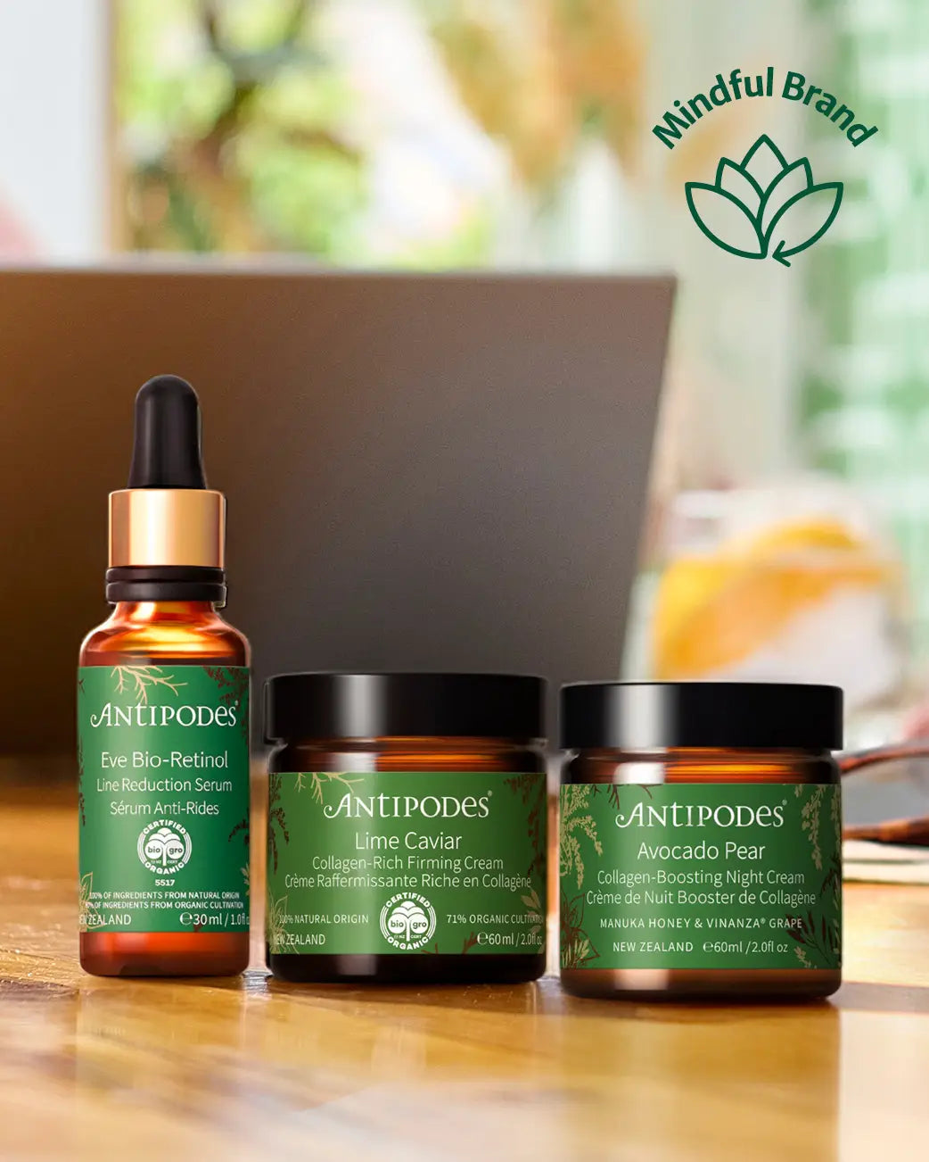 3 Antipodes skincare products on a wooden table against a blurred background.