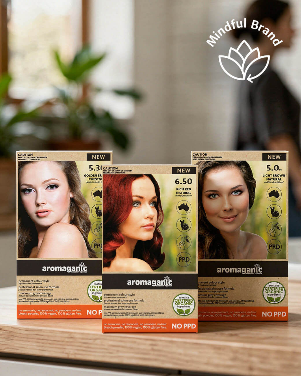 Three boxes of aromaganic hair color on a wooden surface with a blurred background.