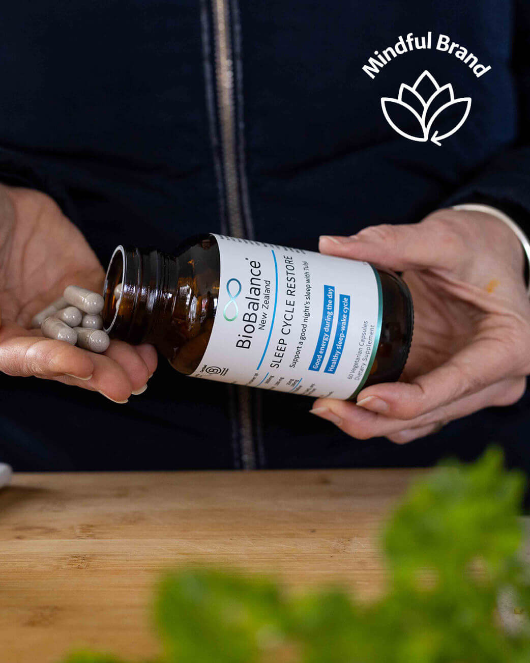 Person holding a bottle of BioBalance supplements with a blurred background.