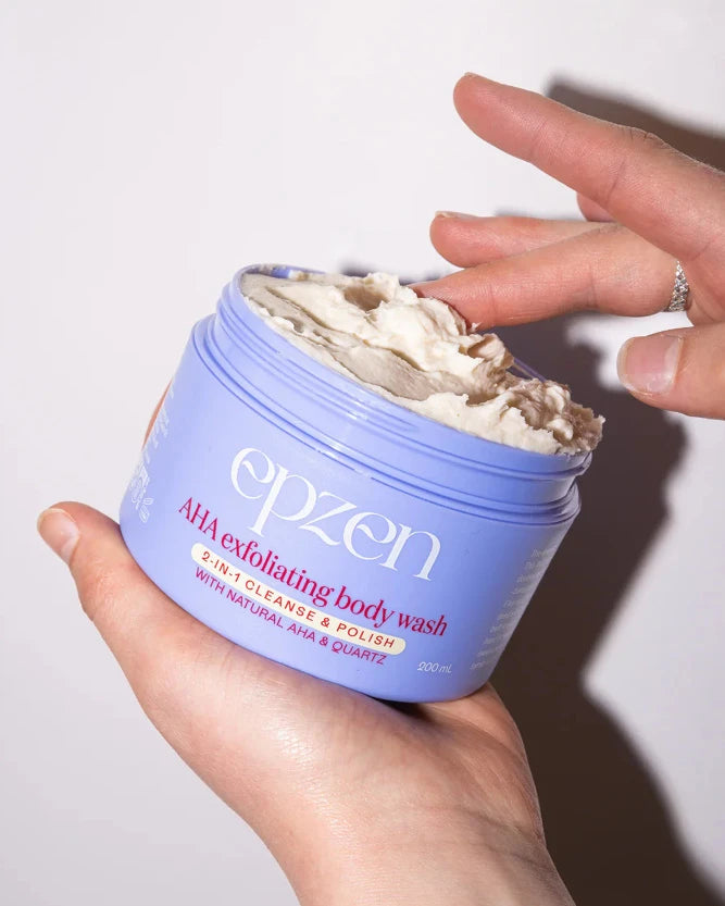 Open jar of epzen exfoliating body wash showing thick texture and person taking some onto their finger.