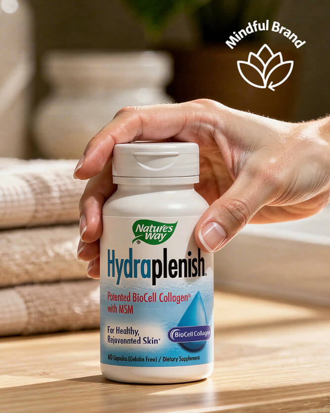 Hand holding a bottle of Nature's Way Hydрапlenish supplement on a wooden surface with 'Mindful Brand' logo in the corner.