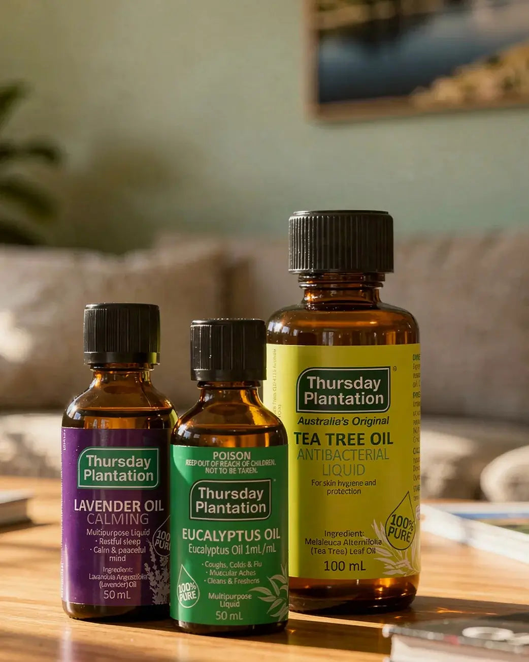 Three bottles of Thursday Plantation essential oils on a wooden surface with a blurred background.